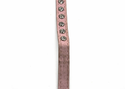 A close-up of a dusty pink faux-leather strap, likely for a belt or watch, featuring a vertical row of silver-toned rhinestone studs on the right side, set against a plain white background.