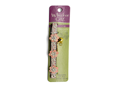 A Whisker City cat collar in floral pink and green patterned fabric with a small gold bell, displayed on its original purple and green retail card packaging against a white background.