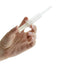A hand holding a translucent white plastic syringe-like applicator or tool against a plain white background.
