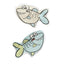 Two cartoon shark-shaped cat toys on a plain white background, one with a beige body and light blue tail, and the other with a light blue body and pale yellow fin.