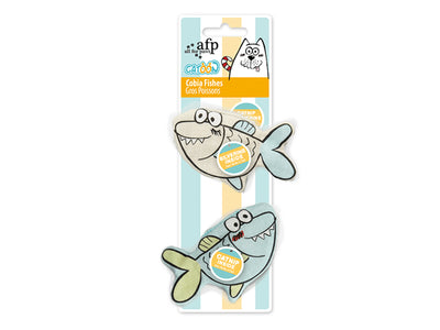 A set of two cartoon shark-shaped cat toys packaged on a vertical cardboard backing with light blue and yellow stripes. The top toy is light blue with a yellow belly patch, and the bottom toy is light green with a yellow belly patch.