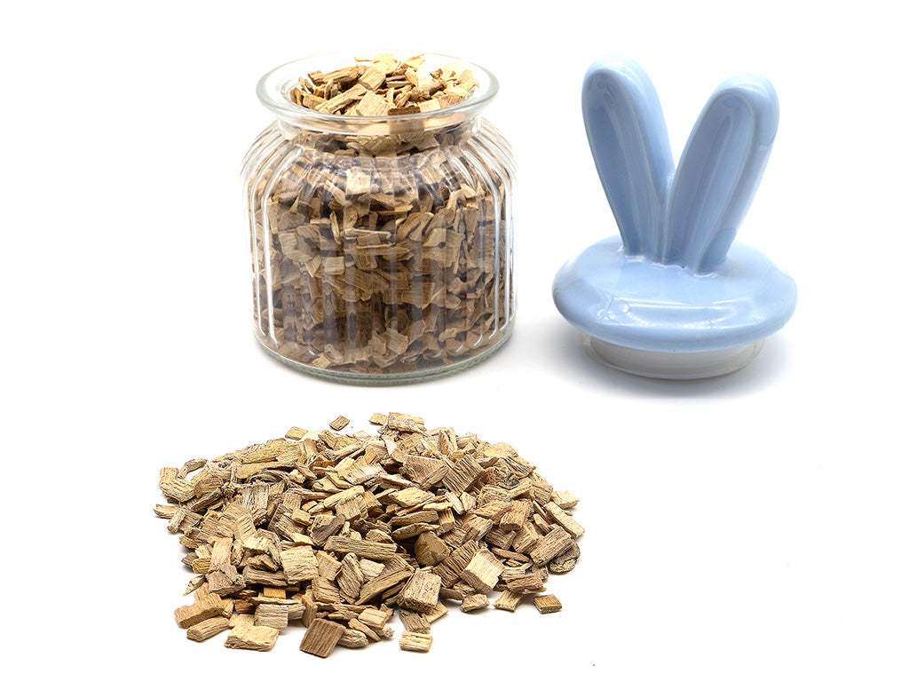 Glass jar with beech chips, a small pile of beech chips on a white background, and a blue rabbit-shaped lid.