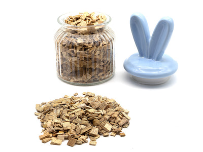 Glass jar with beech chips, a small pile of beech chips on a white background, and a blue rabbit-shaped lid.