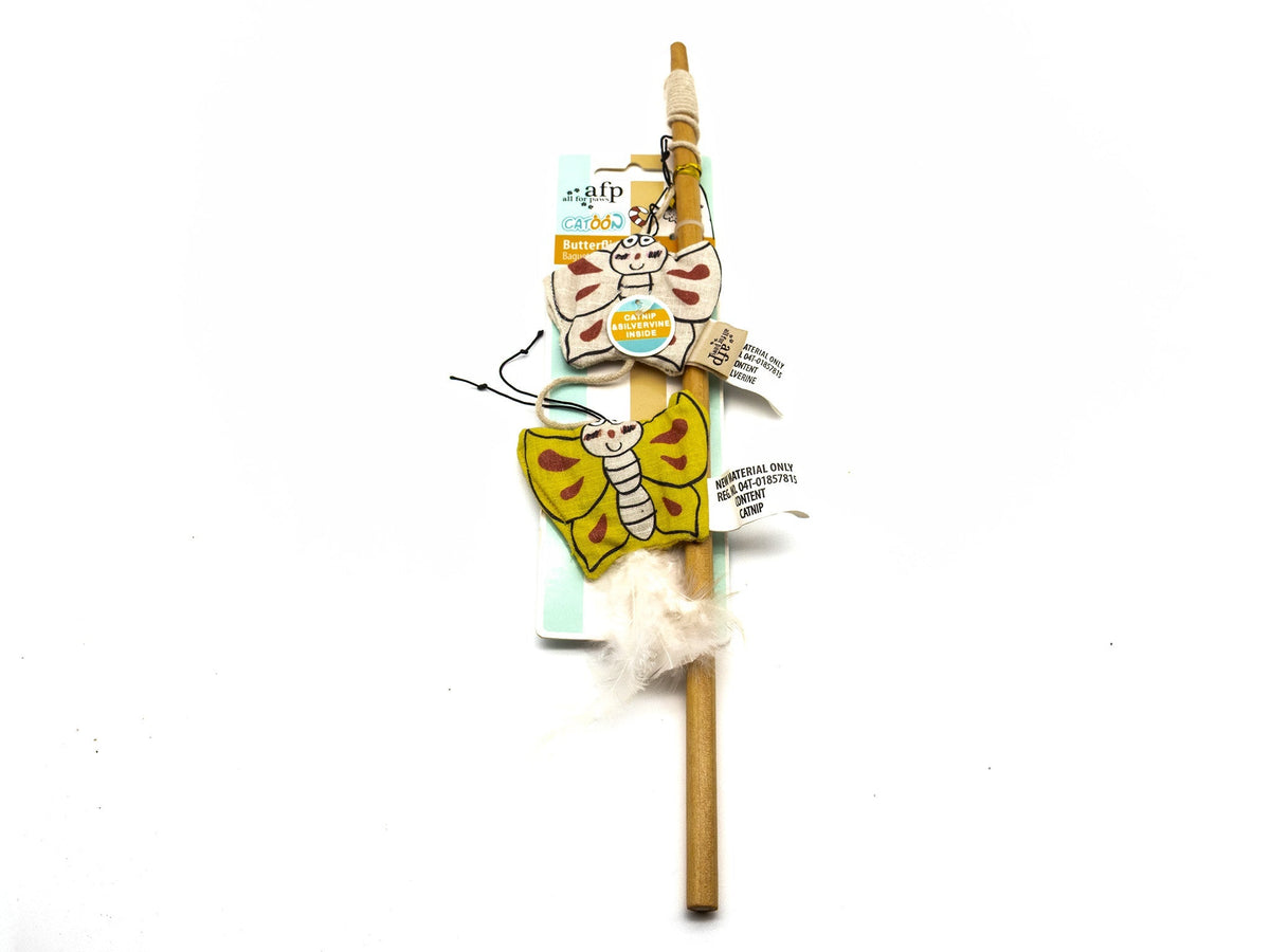 A handmade wooden wand or broomstick decoration featuring two colorful painted butterflies (one yellow and one pinkish-orange) with a white fluffy feather attached near the base, shown on a white background with its retail packaging tags.