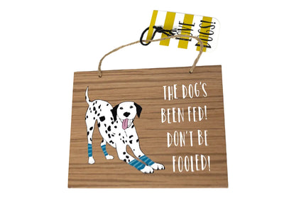 Wooden sign with a cartoon Dalmatian dog and humorous text on a white background