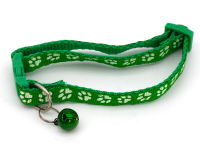 Green cat collar with paw prints and a bell on a white background