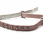 A pink faux-leather cat collar with silver rhinestone studs and a small silver bell, shown on a white background.