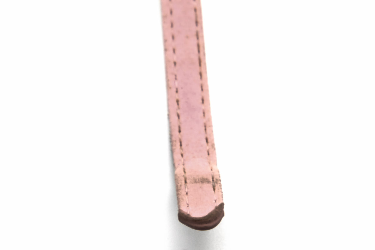 A close-up of a light pink leather strap, likely a watch band or belt, showing the stitched edge and a dark brown tip, set against a plain white background.
