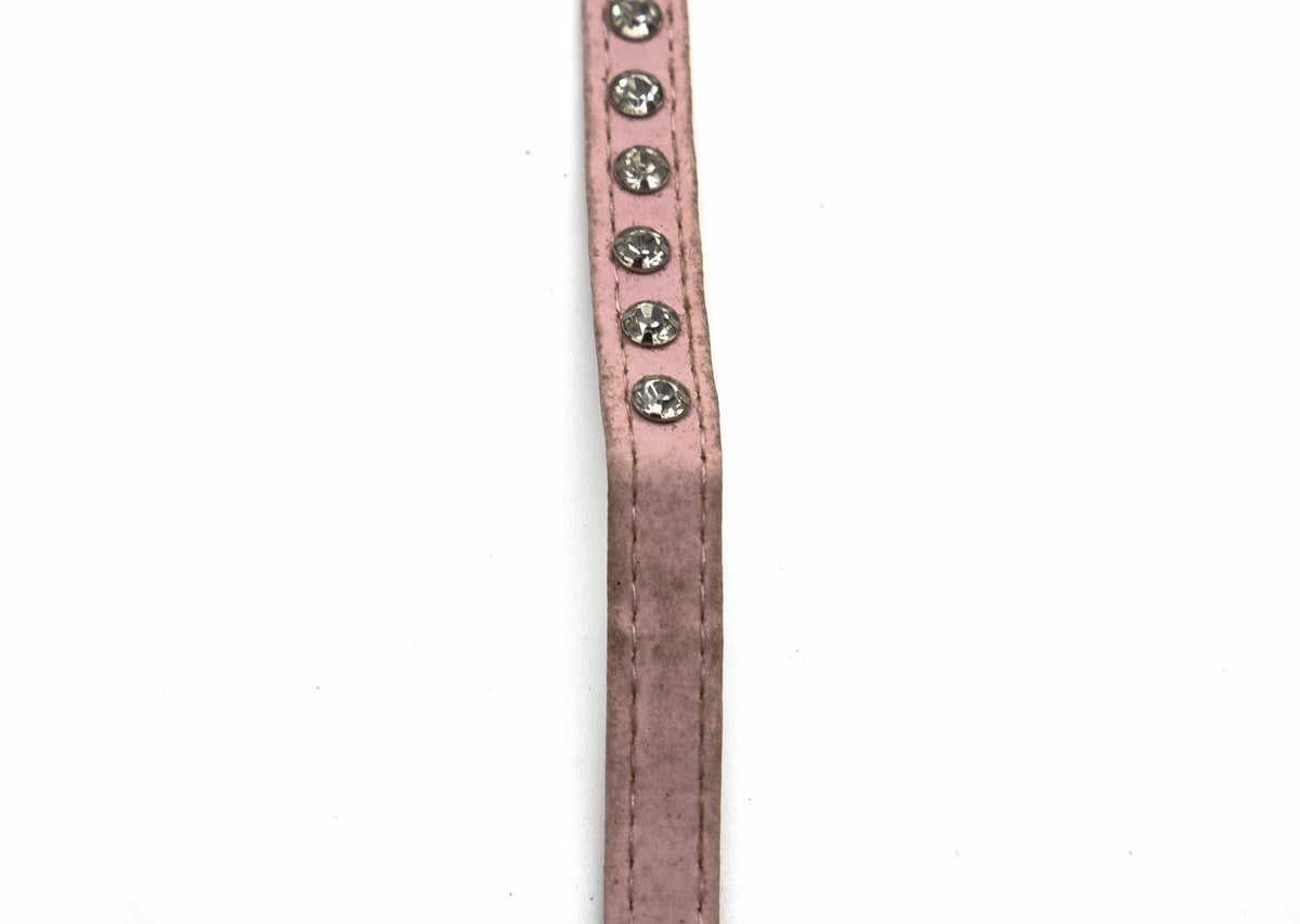 A close-up of a dusty pink faux-leather strap, likely for a belt or watch, featuring a vertical row of silver-toned rhinestone studs on the right side, set against a plain white background.